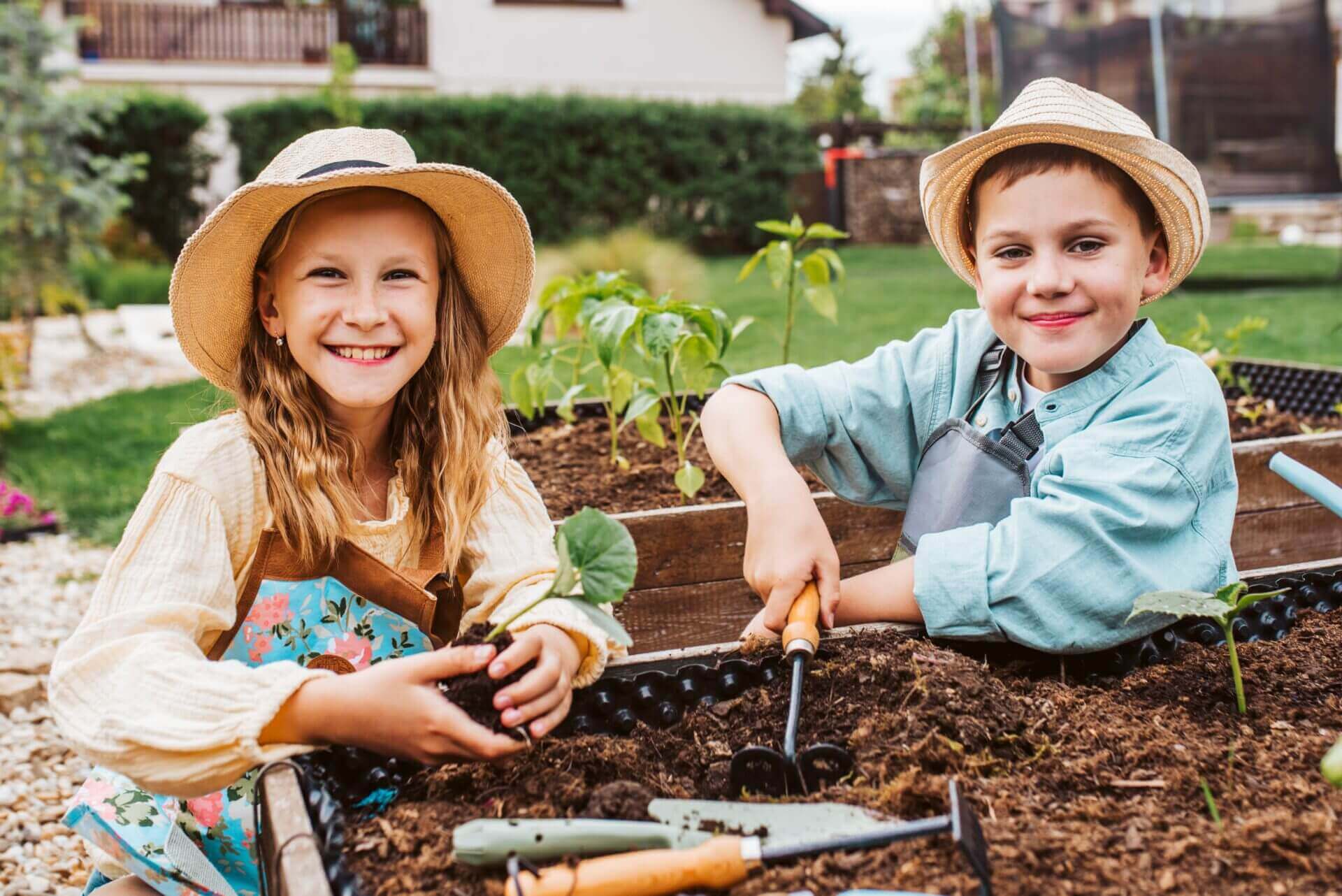 Two children gardening happily in a sunny backyard.