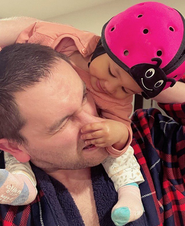 A father and child share a playful, affectionate moment indoors.