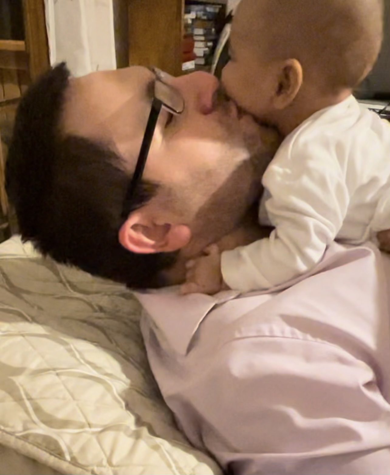 A man lovingly kisses a baby on the cheek.